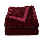 Folded burgundy quilt on a white background