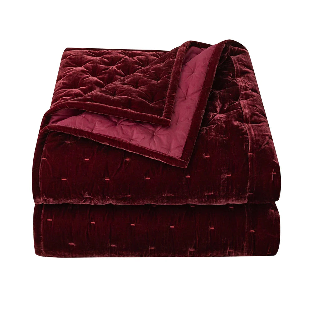 Folded burgundy quilt on a white background