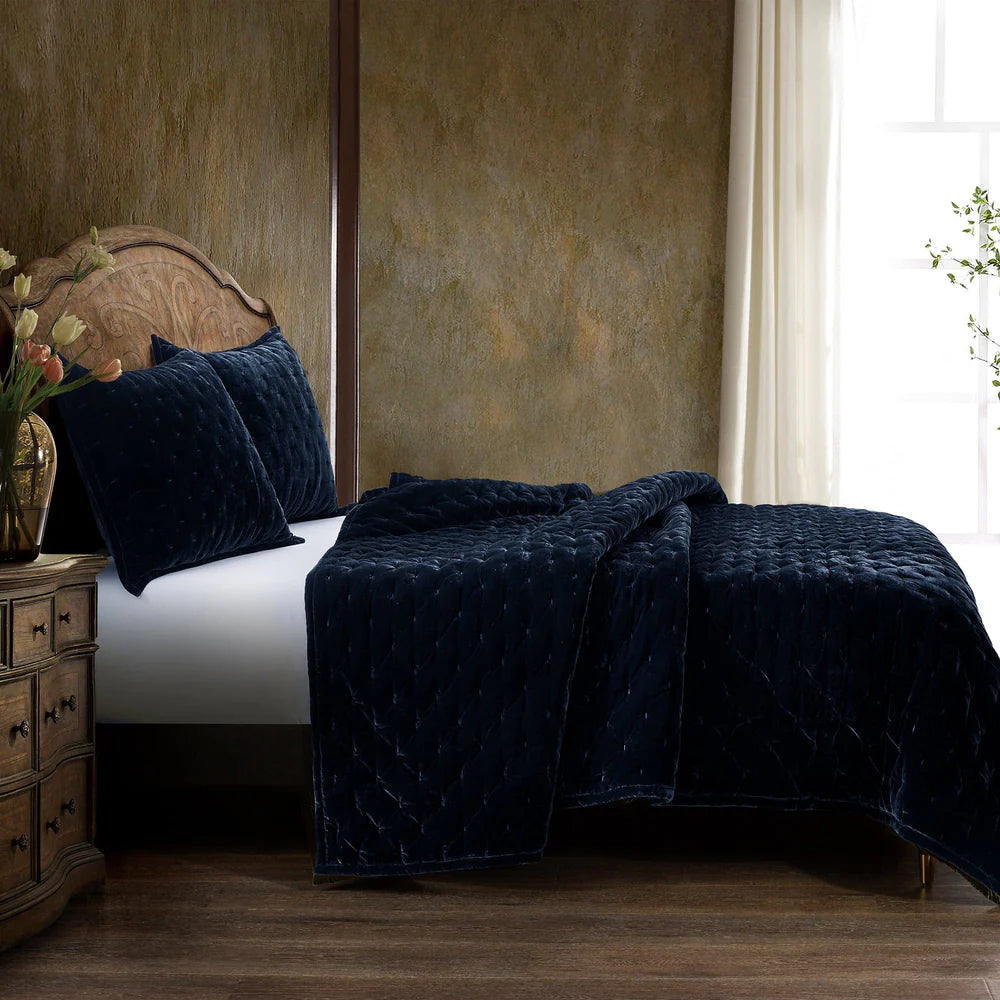 Navy blue textured blanket on a bed in a bedroom setting with a wooden headboard and side table.