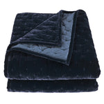 Folded navy blue quilt with textured surface on a white background