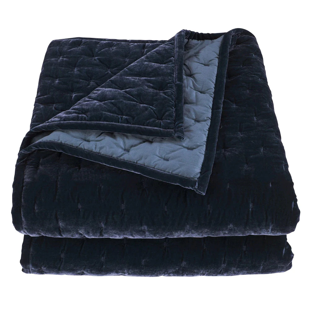 Folded navy blue quilt with textured surface on a white background