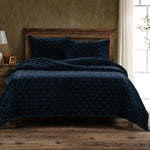 Navy quilt and pillows on a wooden bed in a bedroom setting.