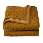 Folded mustard yellow quilt on a white background