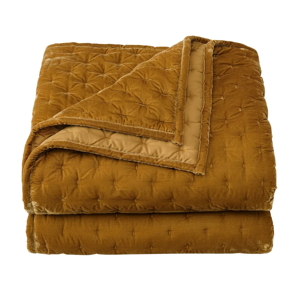 Folded mustard yellow quilt on a white background