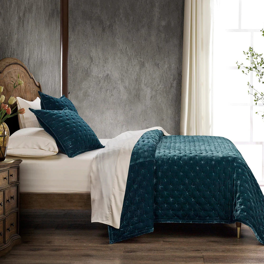 Bedroom with a bed featuring teal quilt and pillows, wooden headboard, and side table.