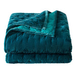 Folded teal quilt on a white background
