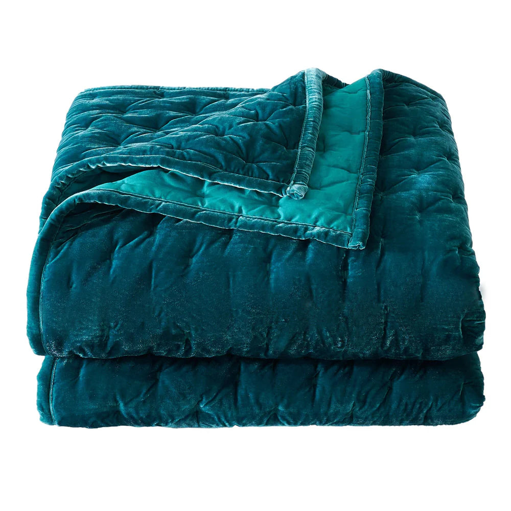 Folded teal quilt on a white background