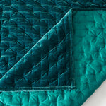 Teal quilt with textured pattern on a white background