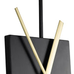 Close-up to a wall clock with a black circular frame and a central black square with gold-colored hands.