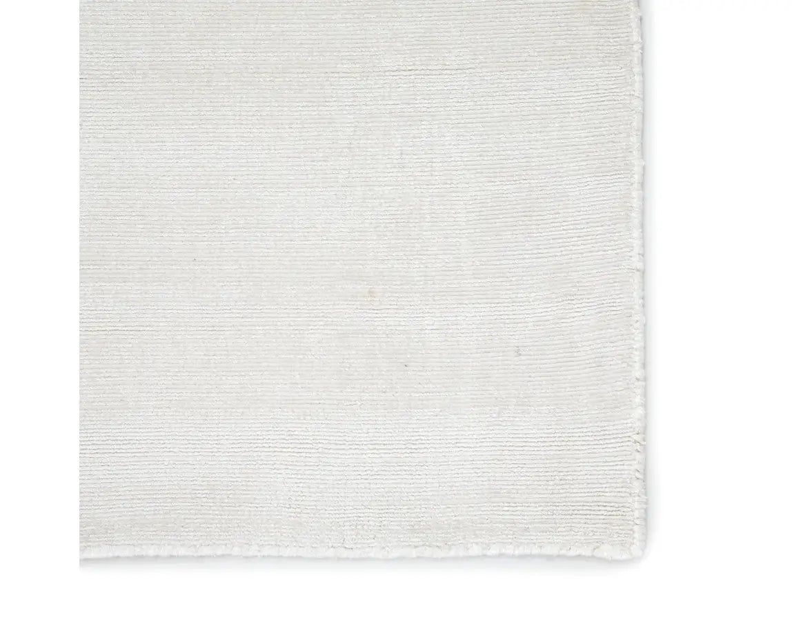 A white, solid color area rug on a plain background.