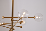 A modern brass chandelier with clear glass shades and adjustable rods, featuring a metal frame.