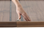 Hand using a tool to adjust a wooden frame with glass panel