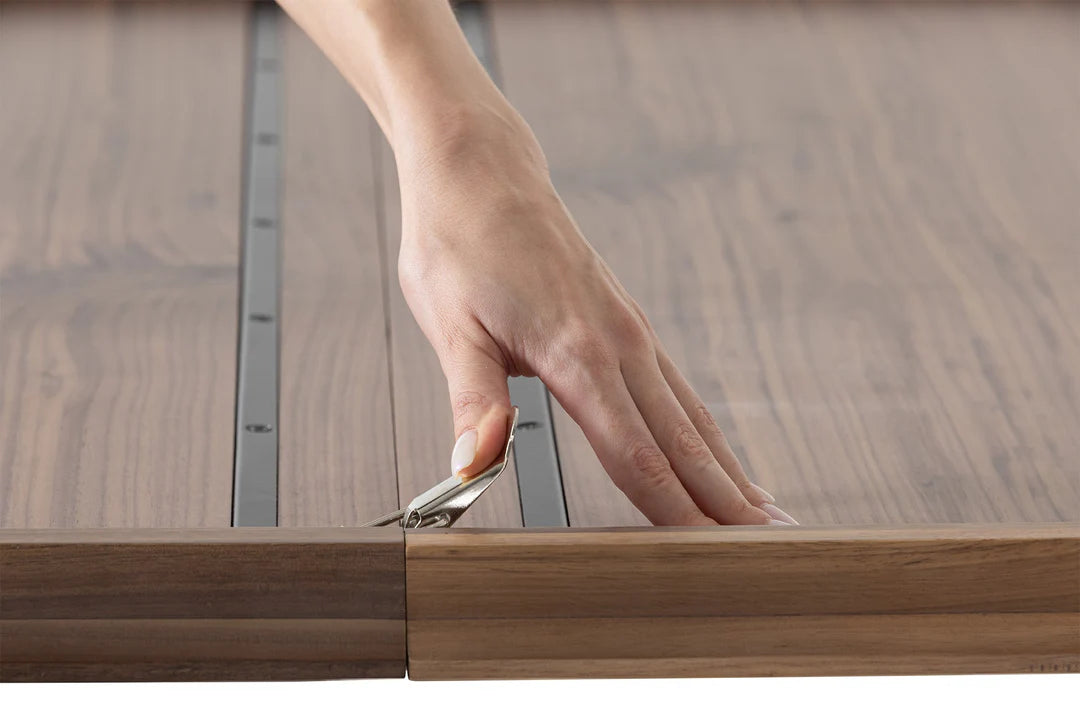 Hand using a tool to adjust a wooden frame with glass panel
