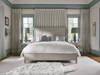 Neatly made bed in a bedroom with curtains and lamps.