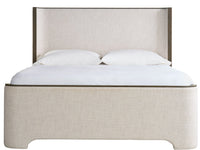 Beige upholstered bed with white bedding on a white background