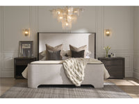 Neatly made bed with decorative pillows and a chandelier in a bedroom setting.