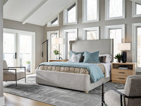 Modern bedroom with a large bed, chairs, and large windows.