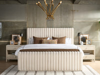 Beige upholstered bed with decorative pillows in a modern bedroom setting.