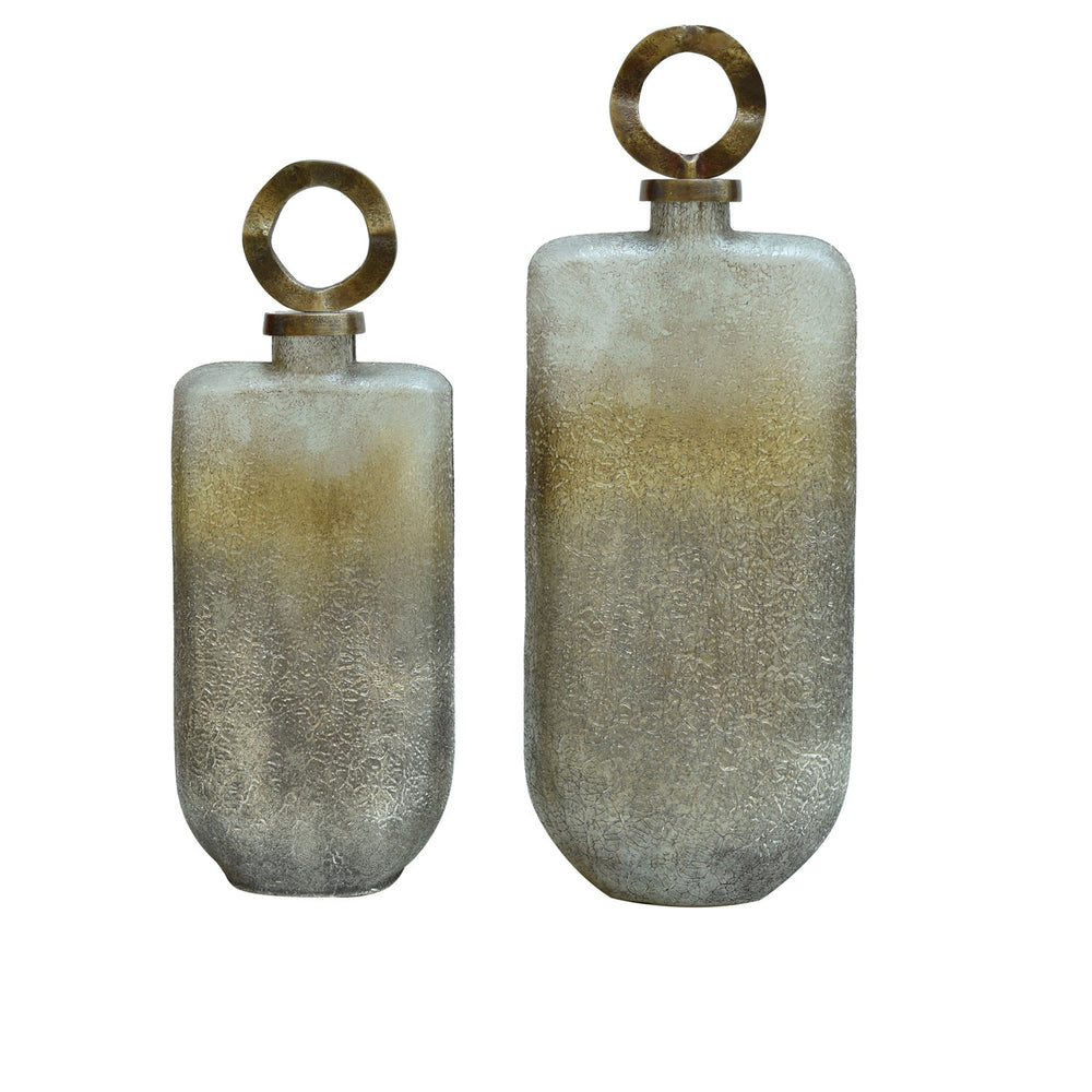 Two cylindrical glass bottles with brass lids, one larger than the other, displayed against a white background.