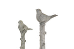 Close-up to Two decorative bird statues on branches against a white background