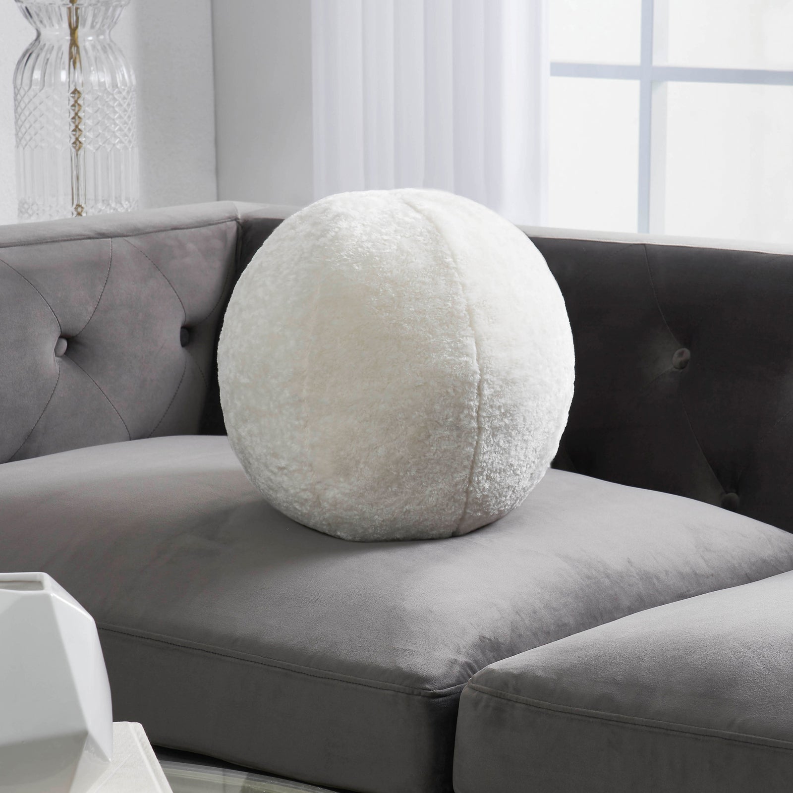 Round accent pillow with a white shearling exterior, solid white color, with a round shape