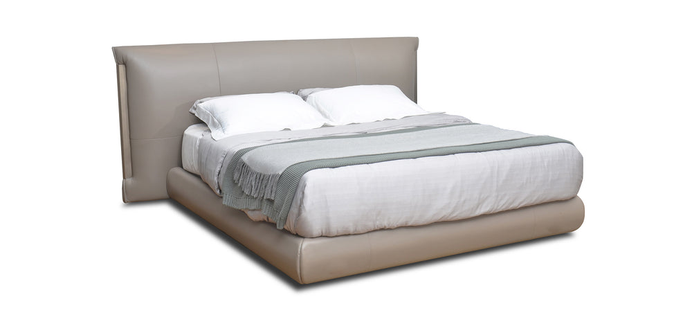 A beige upholstered headboard on a bed with white sheets.