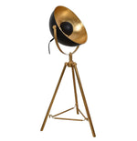 A modern table lamp with an antique brass plated interior, featuring a tripod base and a circular lamp shade, standing upright against a white background.