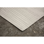 A power loomed area rug in light cream and grey colors with a polypropylene pile and jute backing.