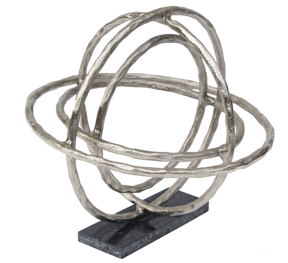 A silver sculpture of a planet with rings, standing upright on a flat surface.