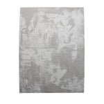 A rectangular jute rug with an abstract off-white and grey pattern.