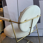 A contemporary brass dining chair with a white seat and backrest, featuring a minimalistic design with subtle gold accents.
